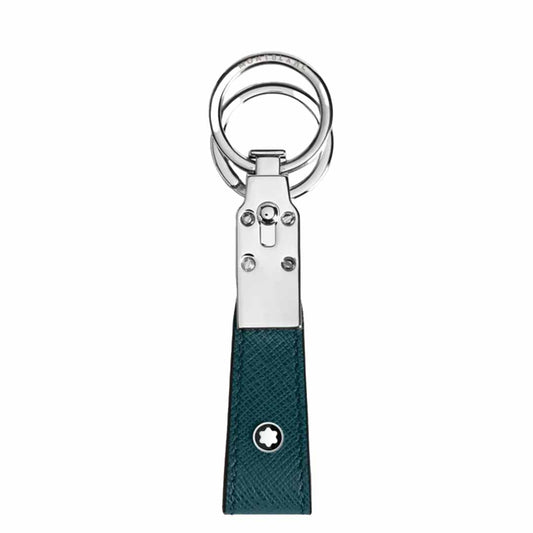 The Montblanc Sartorial Loop Key Fob showcases a stylish design with a silver metal clasp and a textured dark green, full-grain leather strap, accented by a small emblem of a white star within a circle near the bottom.
