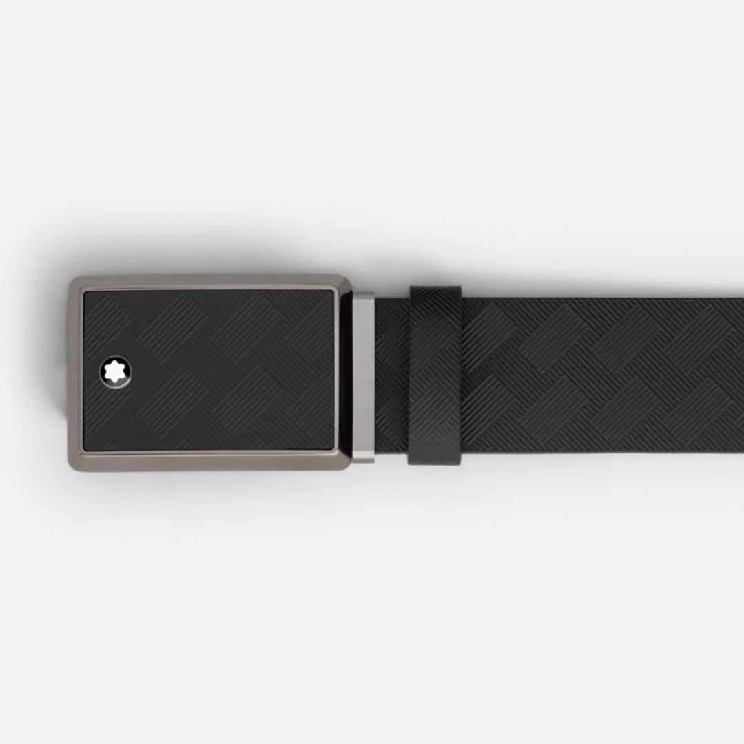 The Montblanc 35mm Leather Belt showcases a black leather strap with a textured rectangular buckle, highlighted by a small star-shaped detail in the corner and adorned with a shiny ruthenium finish. The belt is displayed flat against a plain, light-colored background.