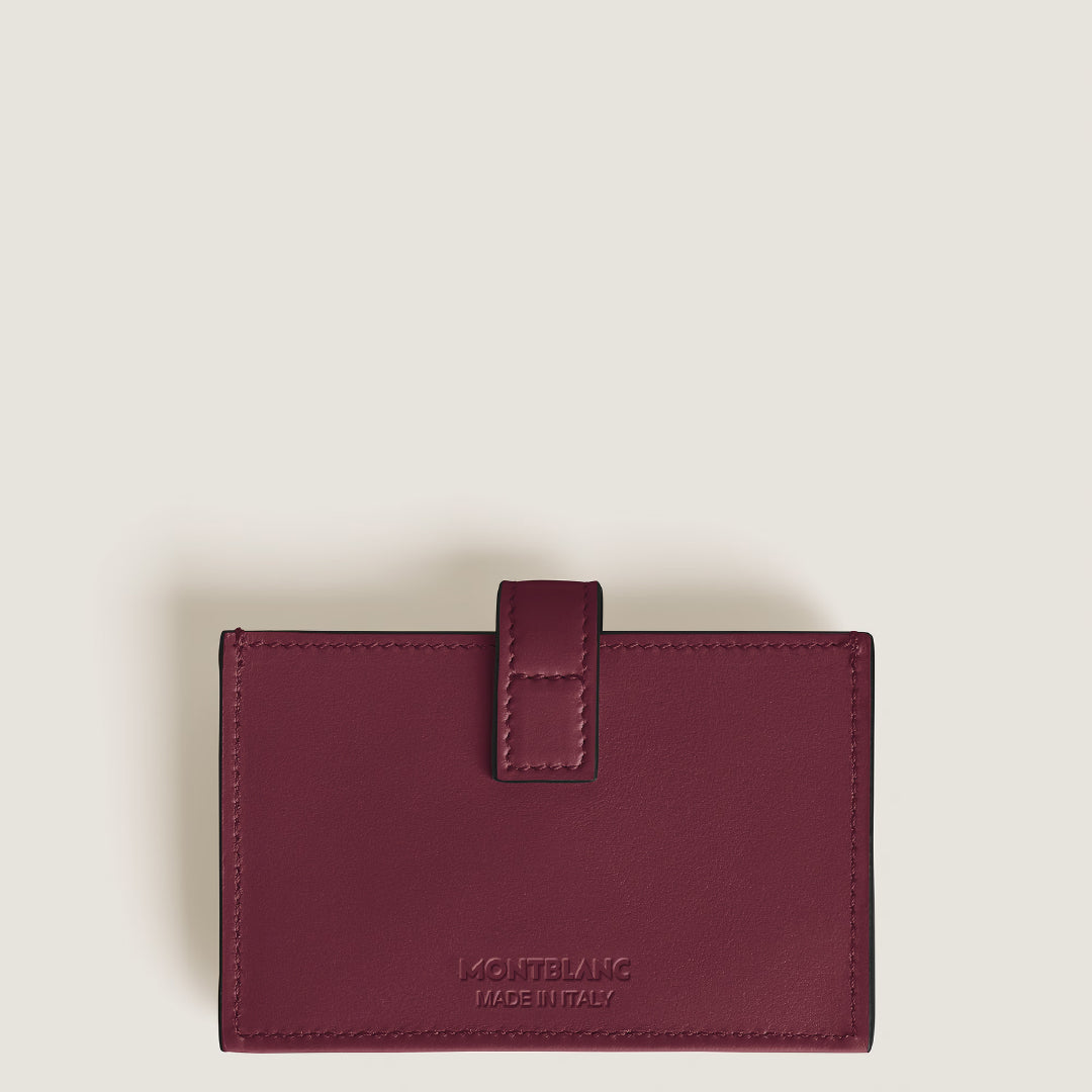 The Montblanc Meisterstuck 5CC Card Holder, crafted in maroon cassis leather with a stitched border and flap closure, is centered on a plain light background. "Made in Italy" is embossed on the lower part, highlighting Montblanc's craftsmanship.