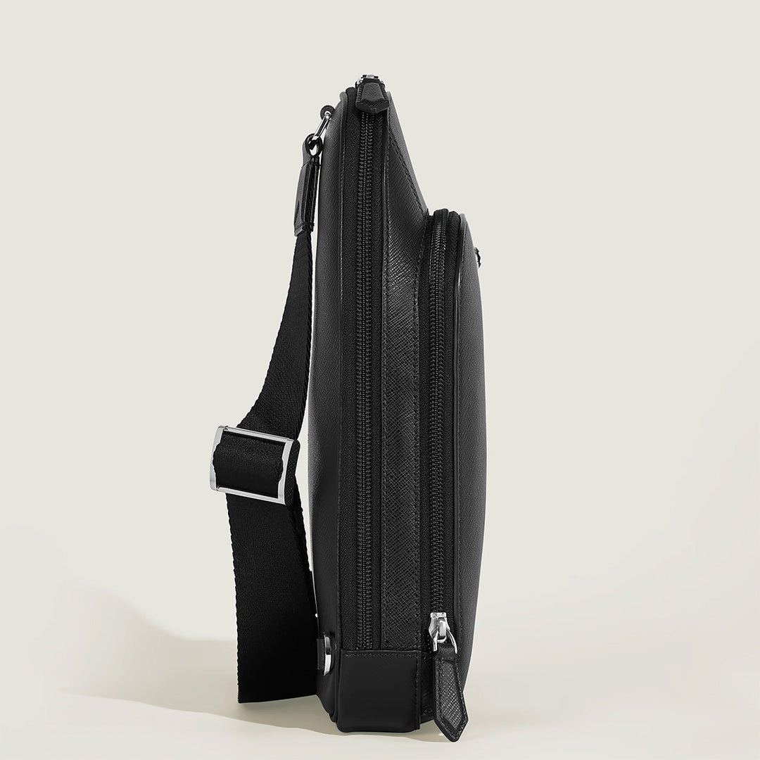 Side view of the Montblanc Sartorial Sling Bag, featuring sleek Saffiano-embossed leather, a zipper closure, and an adjustable shoulder strap on a light surface. The textured leather and silver hardware create a modern and professional look.