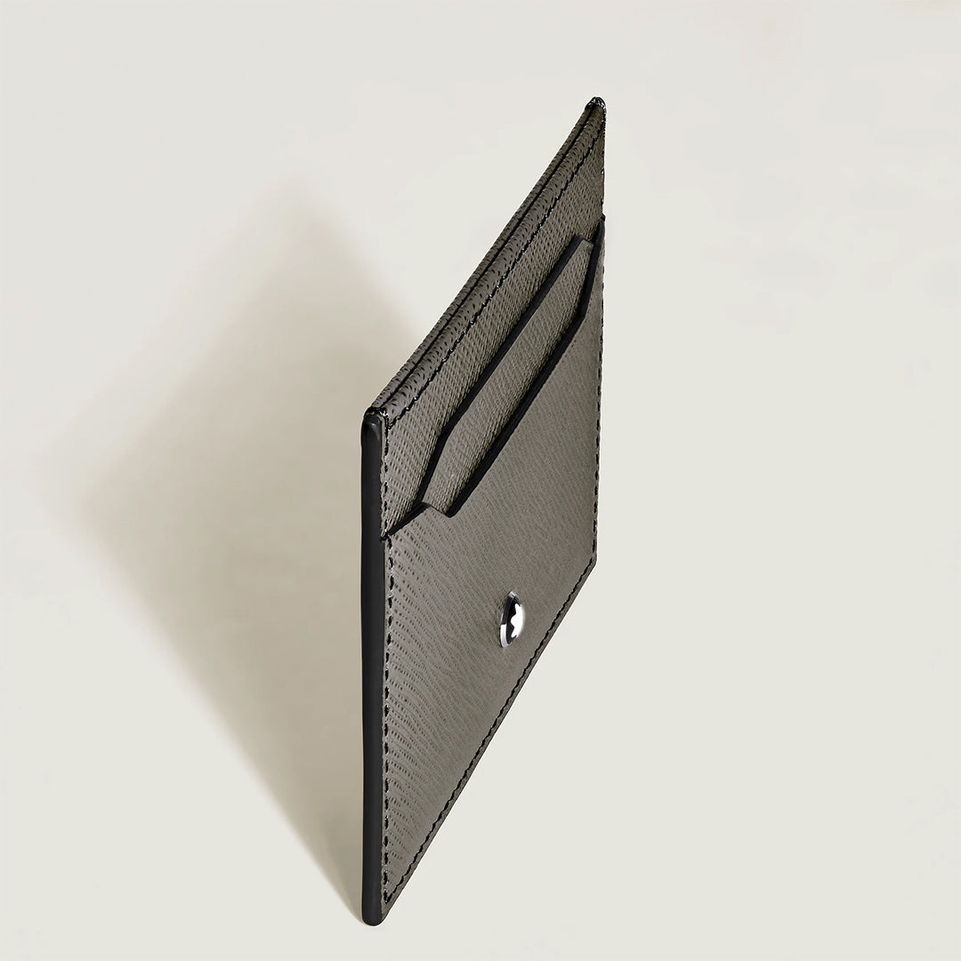 The Montblanc Sartorial Grey 5CC Leather Card Holder features a slim grey Saffiano-printed leather design with visible stitching, five card slots, the iconic Montblanc emblem on the front, and is shown against a plain light background.
