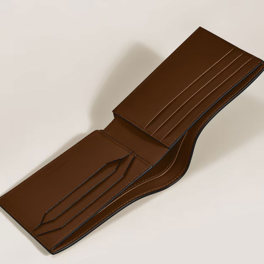 The Montblanc Meisterstück Sfumato 6CC Leather Wallet, in brown leather, is open to show its multiple card slots and compartments—a luxurious Montblanc accessory elegantly displayed on a light surface.