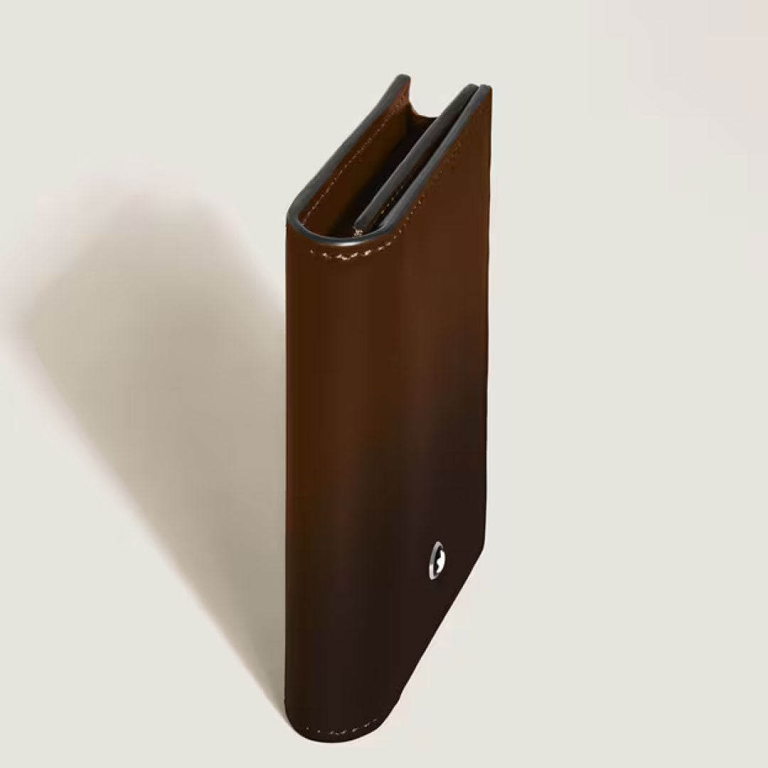 The Montblanc Meisterstuck 4cc Brown Sfumato Leather Card Holder stands upright on a light surface, partially open, with the signature Montblanc emblem on the lower front corner.