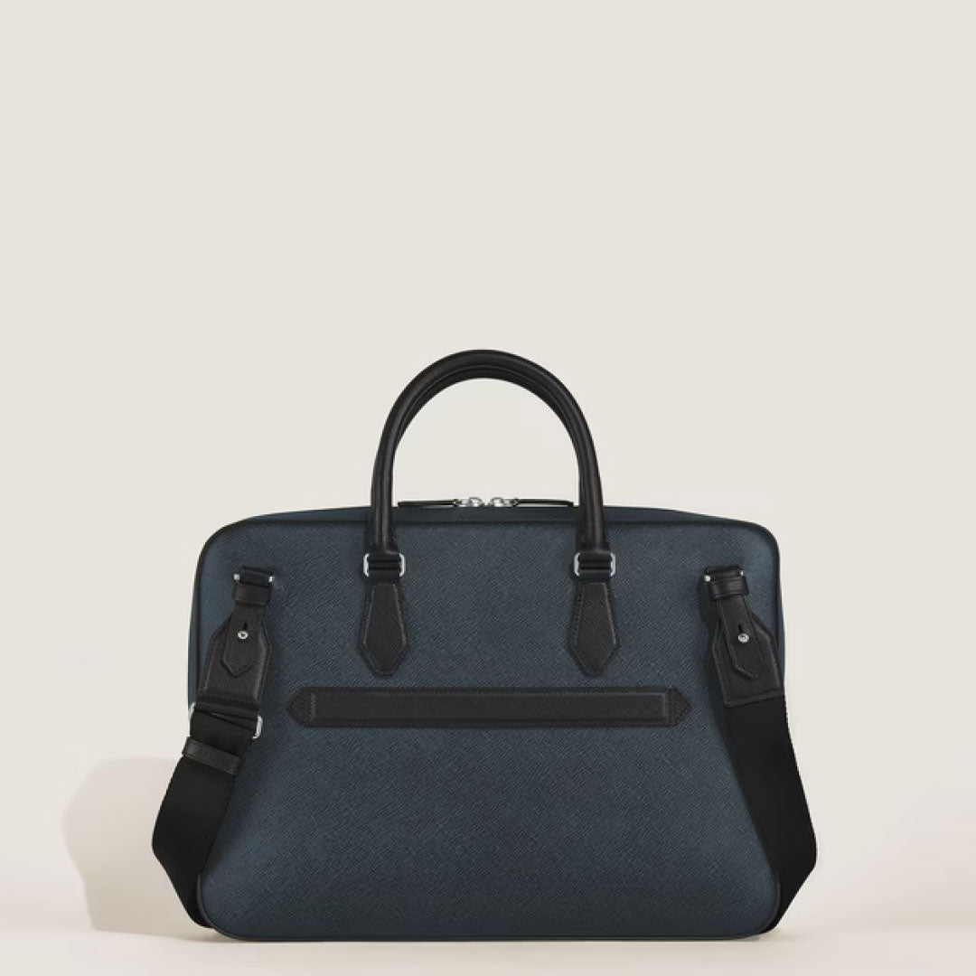The Montblanc Sartorial Thin Document Case Bag is a structured blue leather briefcase featuring black handles, a black shoulder strap, and a horizontal front pocket, displayed against a plain light background.