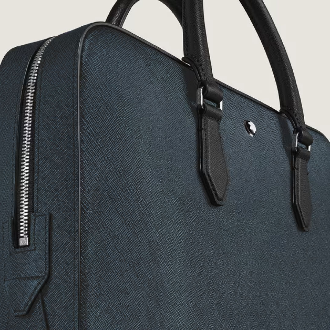 A close-up of the Montblanc Sartorial Thin Document Case Bag, featuring textured dark blue leather, black handles, silver hardware, and a side zipper.