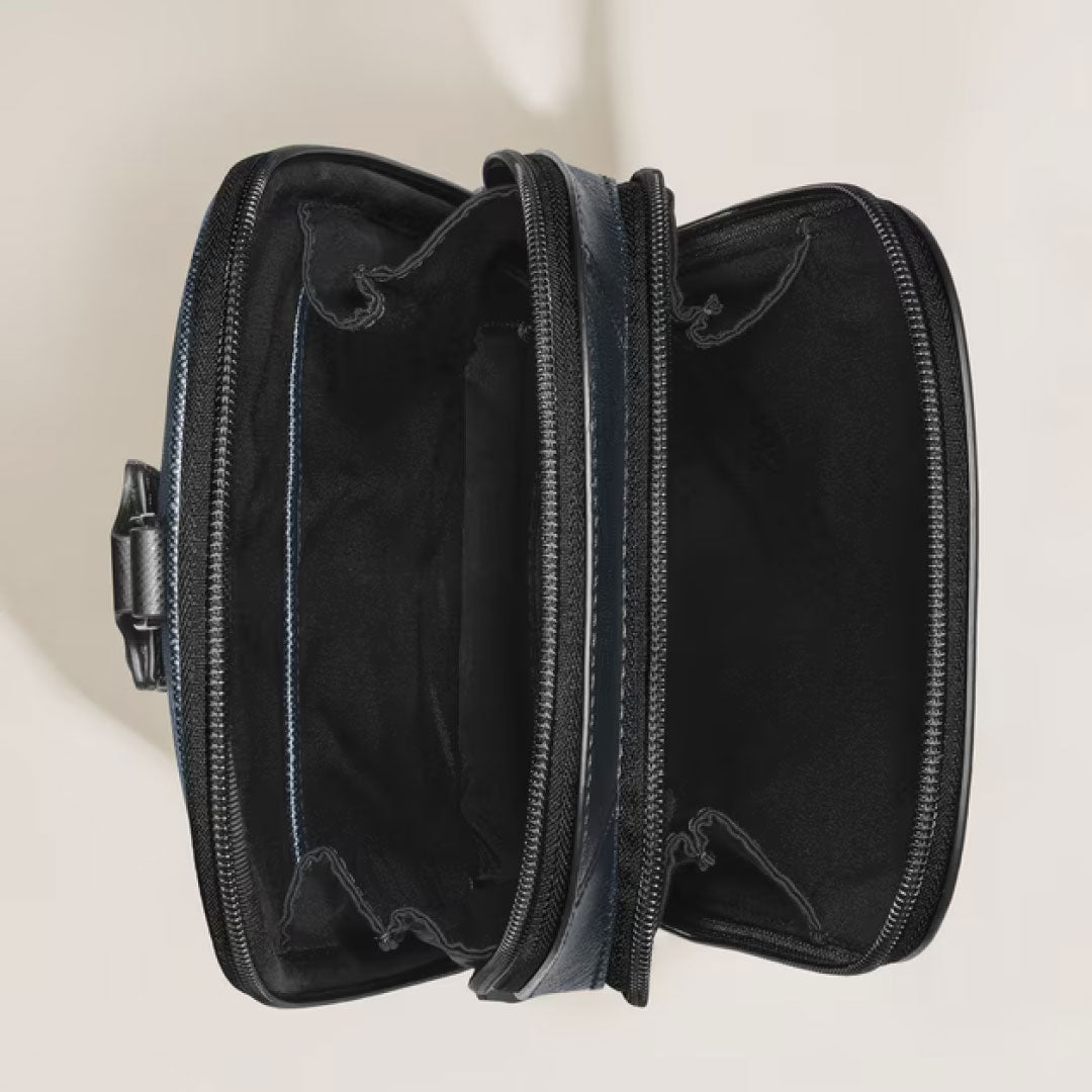 Top-down view of an open Montblanc Sartorial Leather Sling Bag with two empty, fabric-lined main compartments, shown on a light surface.