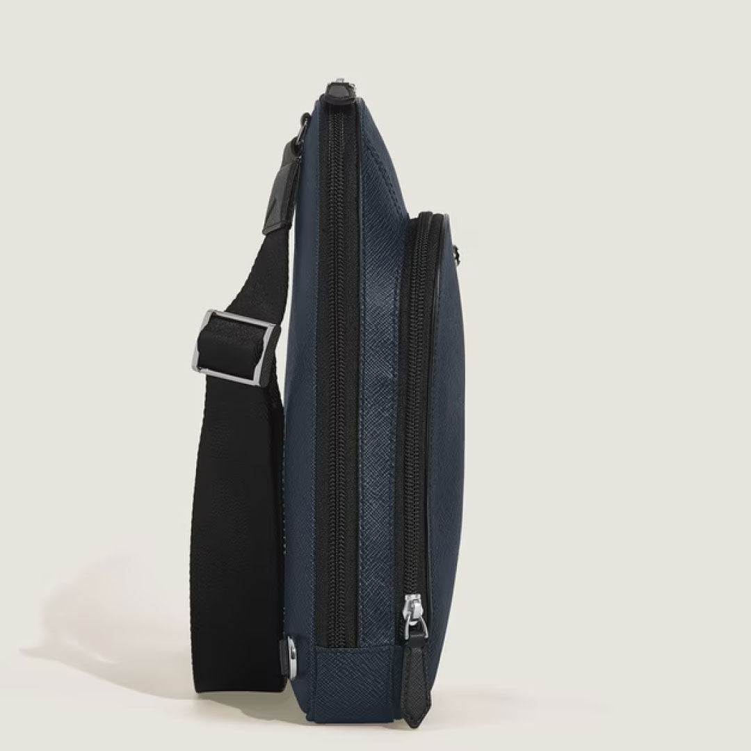 Side view of the Montblanc Sartorial Leather Sling Bag in slim dark blue, featuring a black adjustable strap, silver buckles, and two zippered compartments by Montblanc, set against a plain light background.