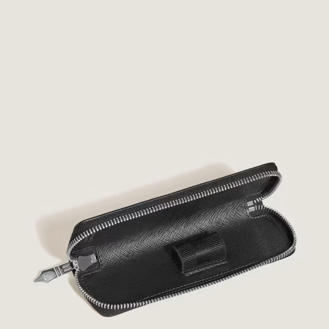 The Montblanc Sartorial Blue Single Leather Pen Pouch with Zip, featuring a textured exterior and an interior elastic loop for one pen, is shown partially open against a light beige background.