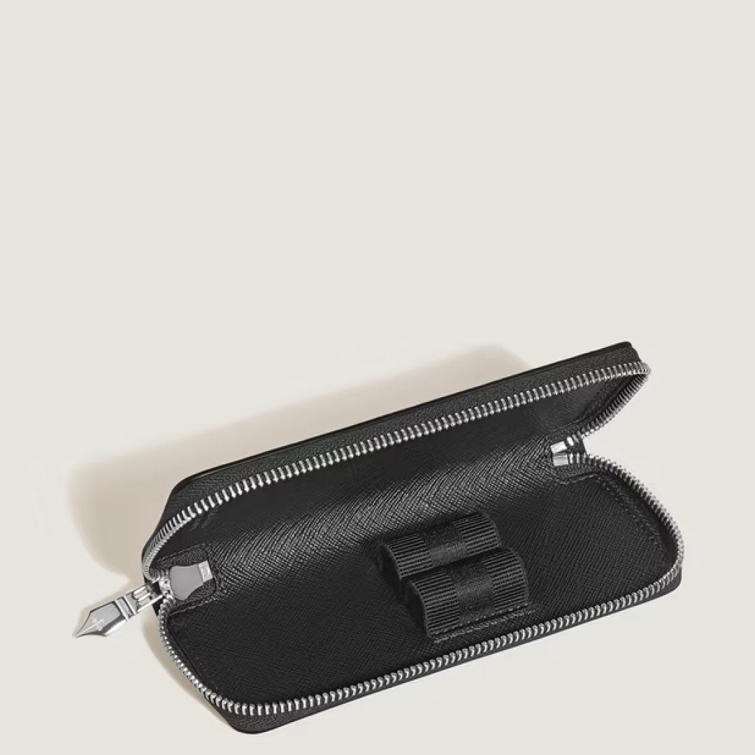 The Montblanc Sartorial Leather 2 Pen Pouch With Zip is shown open, displaying its textured interior and two elastic loops for pens. The black Montblanc case rests on a plain, light background.