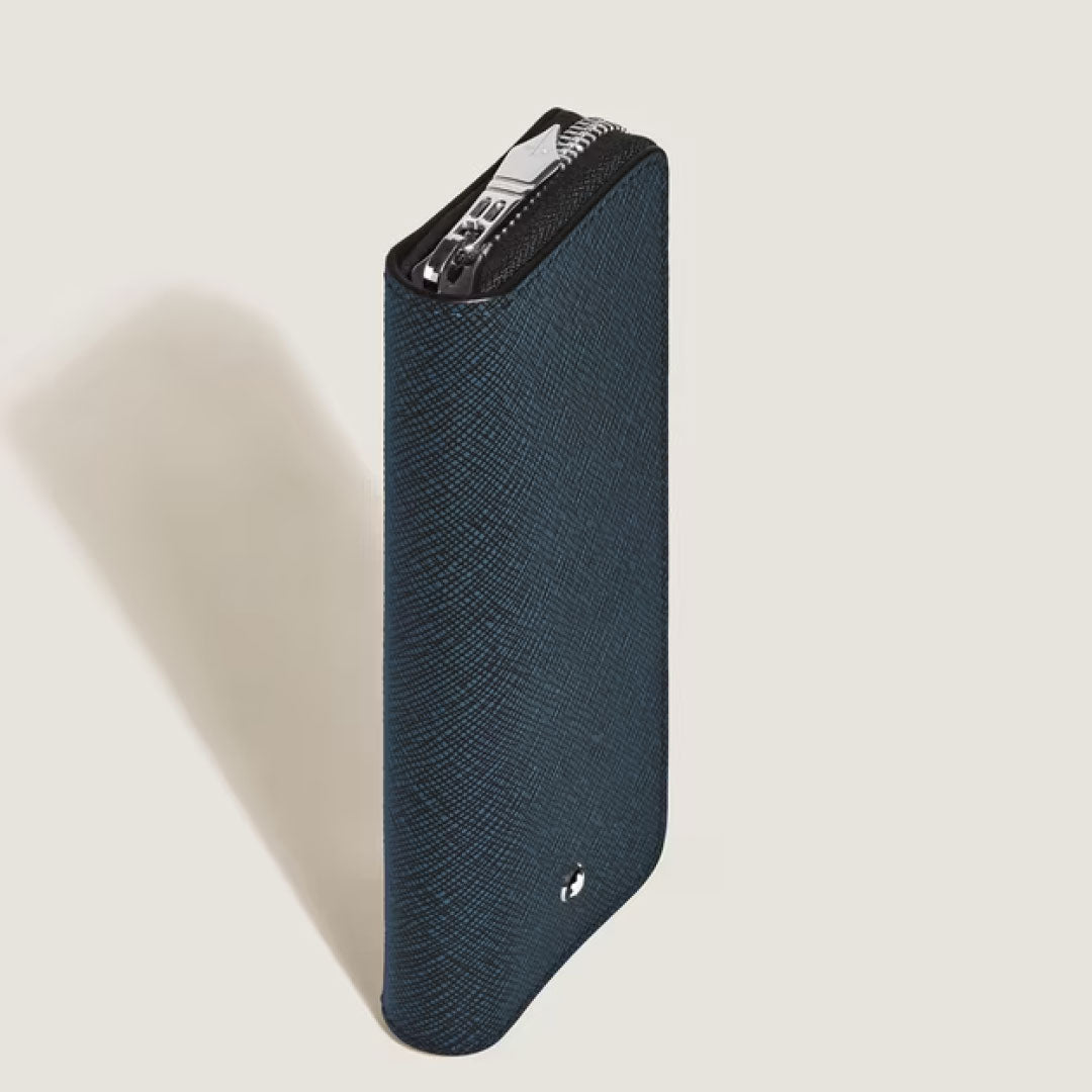 A slim, textured dark blue Montblanc Sartorial Leather 2 Pen Pouche With Zip stands upright against a light background, its metallic zipper partially visible—reflecting the refined style of Montblanc.