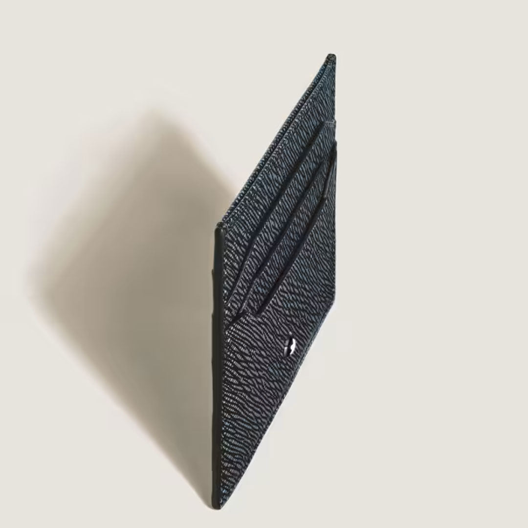 The Montblanc Sartorial Leather 6cc Card Holder stands upright on a light surface, its black textured leather featuring multiple slots and a small white Montblanc emblem on the lower front.