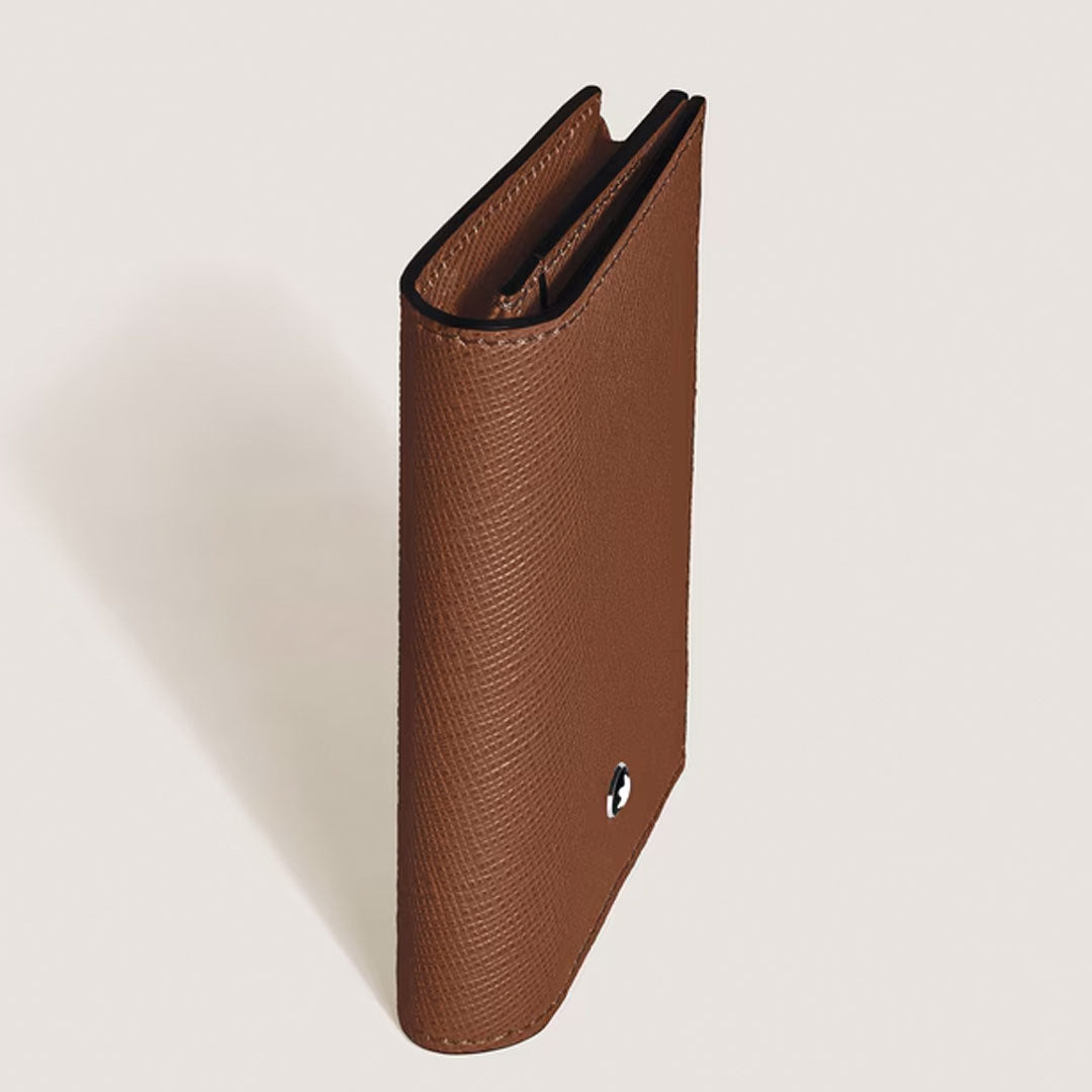 The Montblanc Sartorial 4CC Leather Card Holder by Montblanc stands upright on a light surface, partially open to show its textured leather, four credit card slots, and a small metallic button on the front.