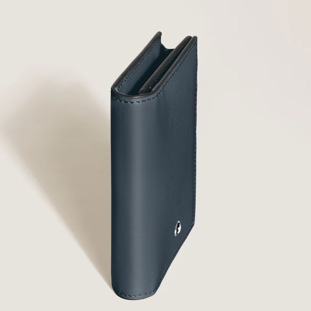 The Montblanc Meisterstuck 4CC Leather Card Holder by Montblanc stands upright on a light beige surface, its closed, dark navy blue calfskin design with visible edge stitching and a small metallic logo highlights its compact elegance.