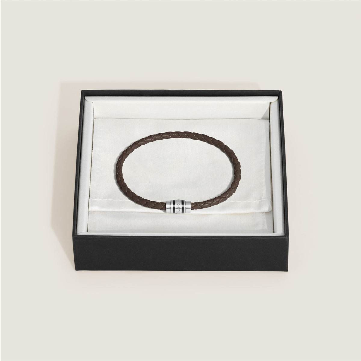A Montblanc 3 Rings Ebony Grain Leather Bracelet with a silver clasp lies in an open black box lined with white fabric.