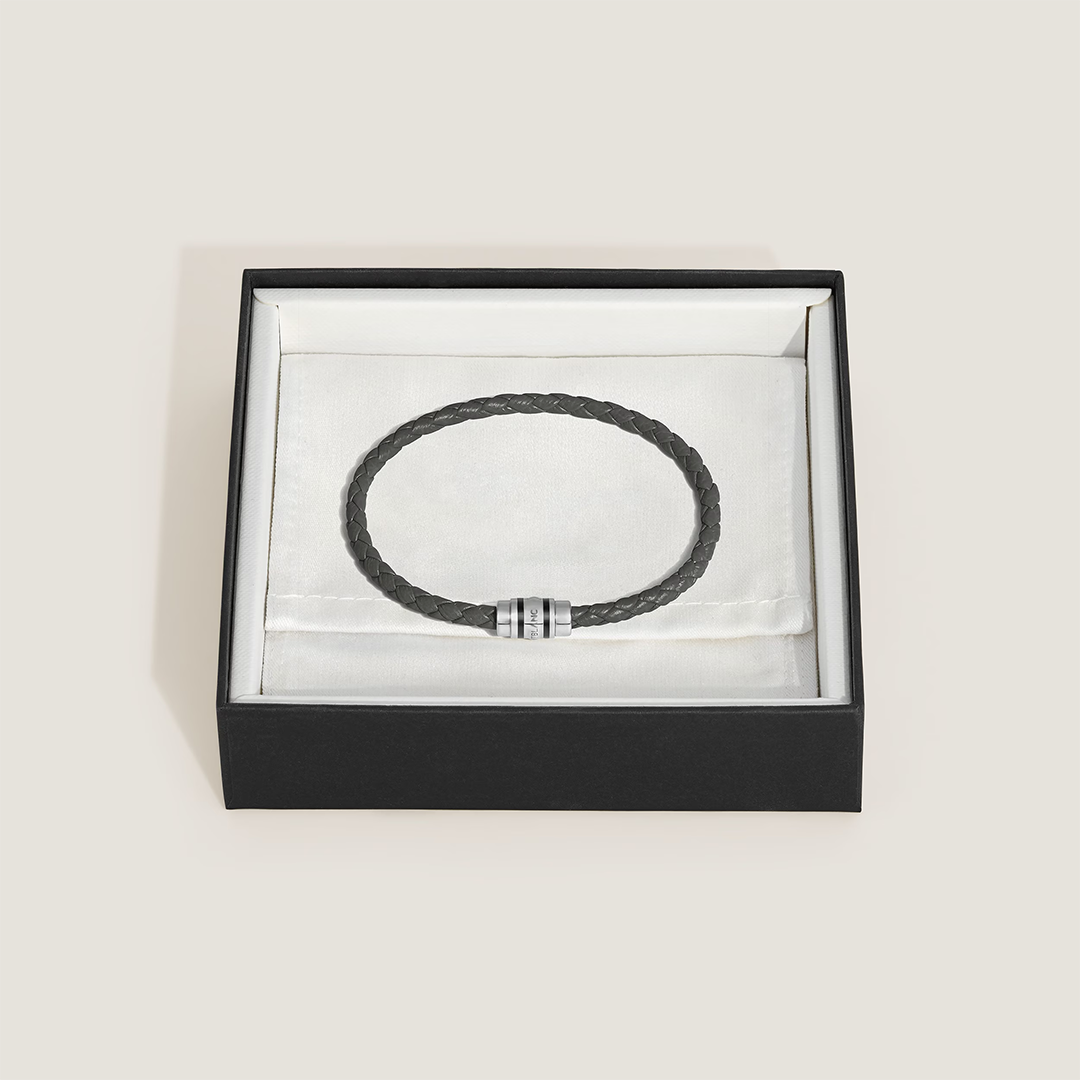 Montblanc 3 Rings Steel Woven Grain Leather Bracelet featuring a dark grey braided band and a silver-toned metal clasp with three engraved rings, displayed in an open black gift box.