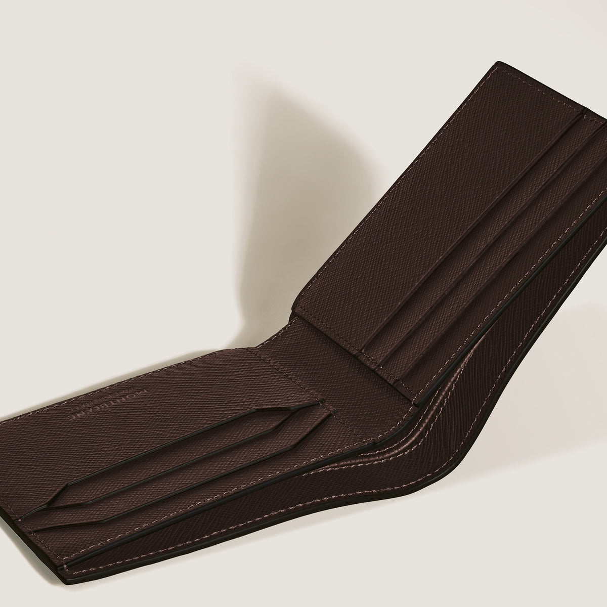 A brown Montblanc Sartorial 6CC Leather Wallet is open on a light surface, showing its embossed leather texture, multiple card slots, and fine stitching.