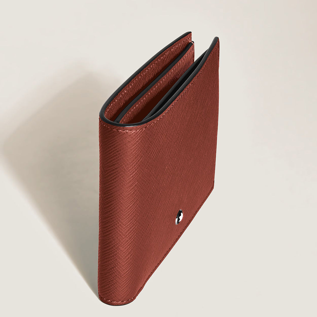 A Montblanc Sartorial 6CC Leather Wallet in brown leather stands upright and slightly open, highlighting its simple, elegant design with a small circular Montblanc metal emblem on the front. The background is plain and light-colored.