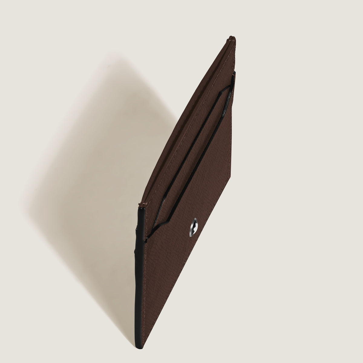 The Montblanc Sartorial 5CC Leather Card Holder by Montblanc is shown standing upright in brown embossed leather with a button closure, set against a light backdrop and casting a soft shadow to the left.