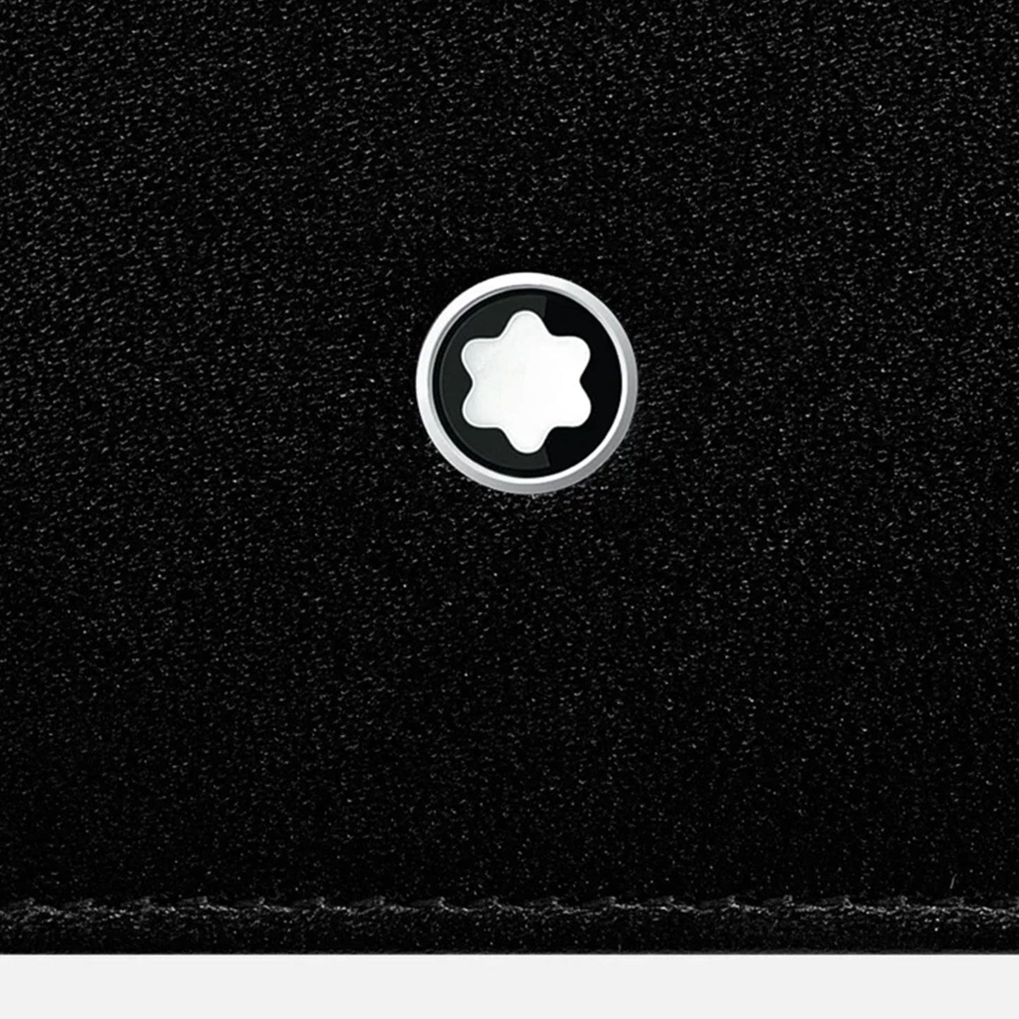 Close-up of the Montblanc Meisterstück Black Leather Wallet's full-grain cowhide leather surface showcasing a metallic circular emblem adorned with a white star design at its center.