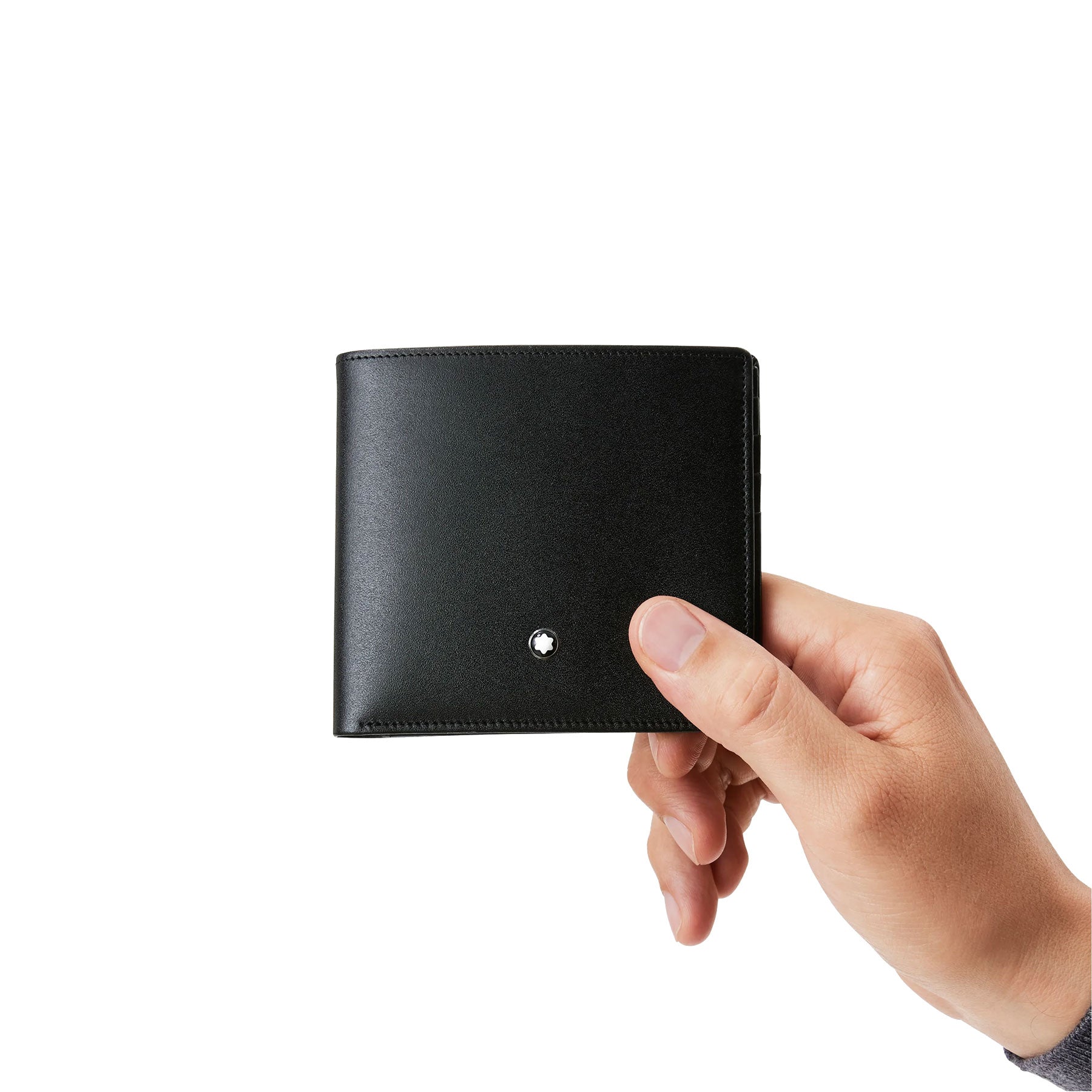 A hand is holding a Montblanc Meisterstuck 8cc Leather Wallet crafted from European full-grain cowhide against a plain white background. The sleek black leather showcases a small, circular emblem on its surface, with credit card pockets inside for organization and style.