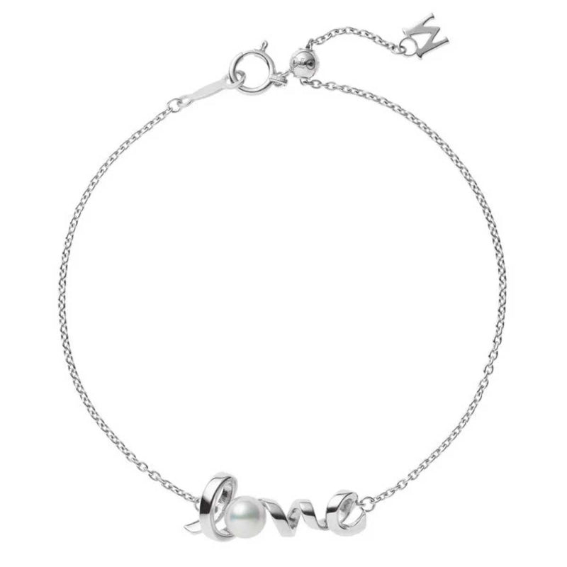 The Mikimoto 18K White Gold Akoya Cultured Pearl Bracelet features a delicate chain with the word "love" intricately woven into its design, complemented by a small Akoya cultured pearl accent. An elegant charm adorned with the letter "M" hangs near the clasp.