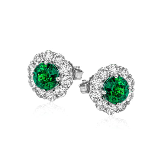 A pair of Simon G. 18K White Gold Diamond and Emerald Stud Earrings, featuring vintage-inspired design in silver, highlights vibrant green center stones encircled by a halo of dazzling clear stones set against a white gold backdrop.