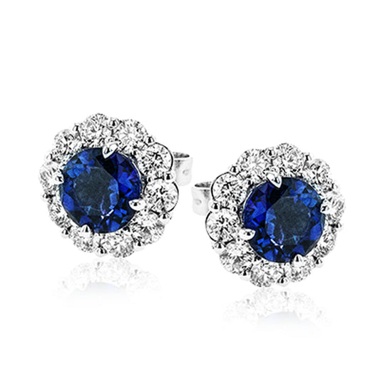 The Simon G. 18K White Gold Sapphire with Diamond Stud Earrings by Simon G features elegant stud earrings adorned with large round sapphires encircled by a halo of smaller sparkling diamonds, set in an 18 karat white gold setting.
