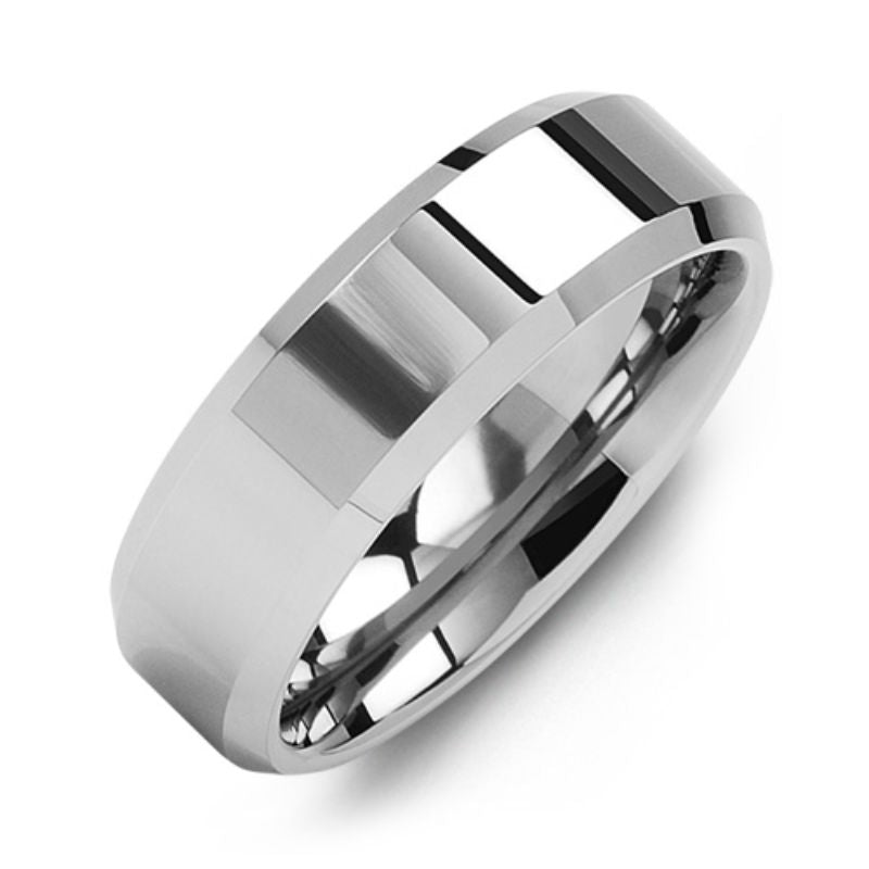 The Madani Polished Beveled Tungsten Wedding Band, designed by Madani, gleams with its silver-toned finish against a simple white backdrop. This ring showcases a sleek, reflective surface and features slightly beveled edges that encapsulate a modern, minimalist aesthetic.