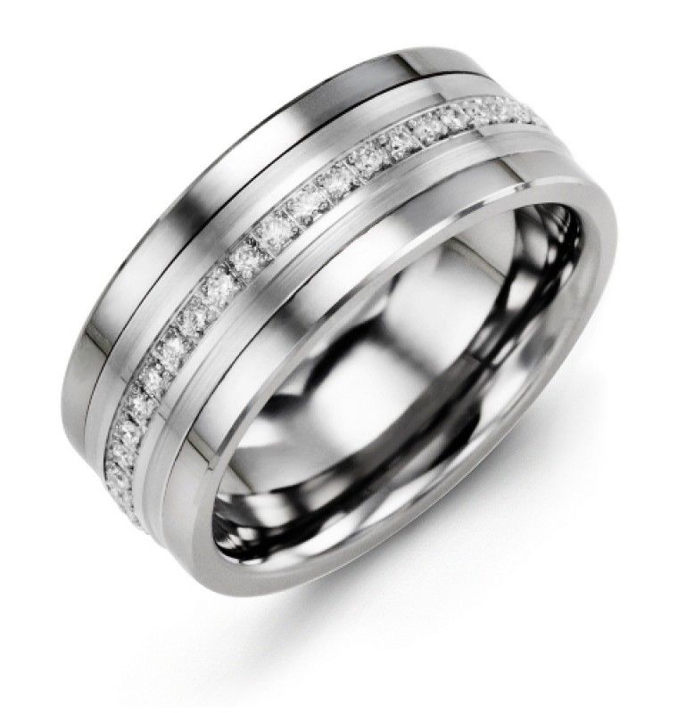 The Madani Tungsten and 10 Karat White Gold with Eternity Round Brilliant Diamond Wedding Band features a wide 9mm band adorned with a central row of small, round brilliant diamonds encircling it. This sleek ring by Madani boasts a smooth, polished finish and modern design that highlights its elegant craftsmanship.