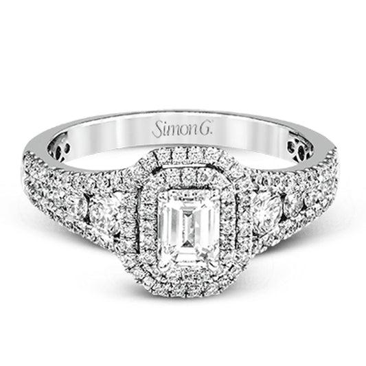 Introducing the Simon G. 18K White Gold Emerald Diamond Ring by Simon G. This exquisite engagement ring features a central emerald-cut diamond encircled by a double halo of smaller diamonds, and its band is adorned with additional diamond accents, seamlessly combining timeless elegance with contemporary refinement.
