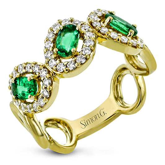 A Simon G. ring crafted in 18 Karat yellow gold, showcasing three oval emerald gemstones, each encircled by a halo of small round diamonds, with the inner band engraved with "Simon G.