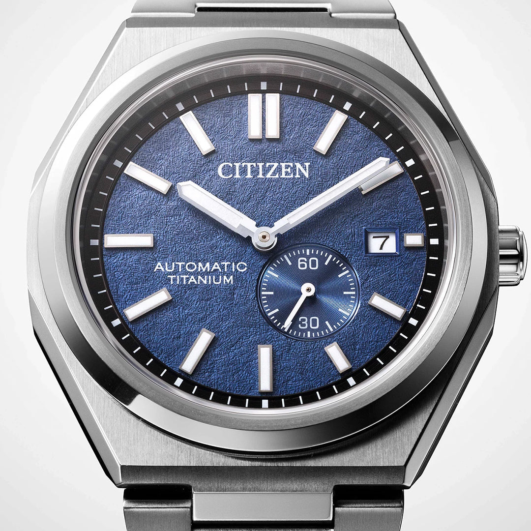 Close-up of the CITIZEN Zenshin Mechanical Automatic 40.5mm Watch, showing its textured blue dial, silver markers and hands, small seconds subdial at 4 o’clock, a date window at 3 o’clock, and "Automatic Super Titanium™" on the face.