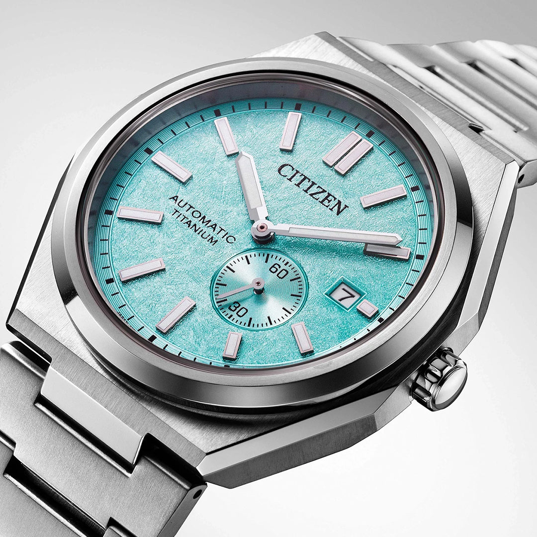 A close-up of the CITIZEN Zenshin Mechanical Automatic 40.5mm Watch featuring a turquoise textured dial, silver markers, date display, small seconds subdial, and Super Titanium™ case with stainless steel bracelet.