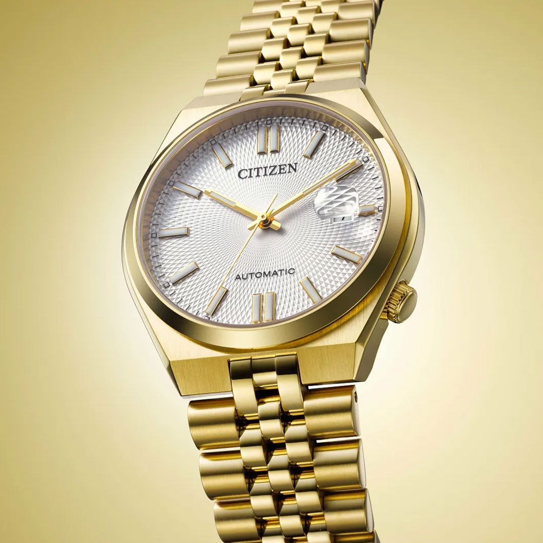 Introducing the CITIZEN TSUYOSA 60 Automatic 40mm Watch: a yellow gold-tone timepiece by CITIZEN, showcasing a white textured dial with gold hour markers and a date window, powered by the automatic calibre 8310. This modern sports watch is paired with a matching gold link bracelet and presented against a vibrant yellow gradient background.