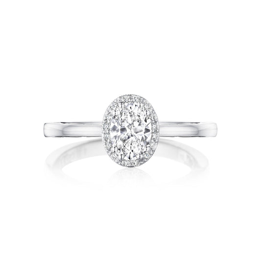 A Tacori engagement ring, featuring an oval diamond at the center surrounded by a halo of sparkling diamonds. The Tacori Coastal Crescent design shines with its sleek and polished 14K white gold band that beautifully reflects light.