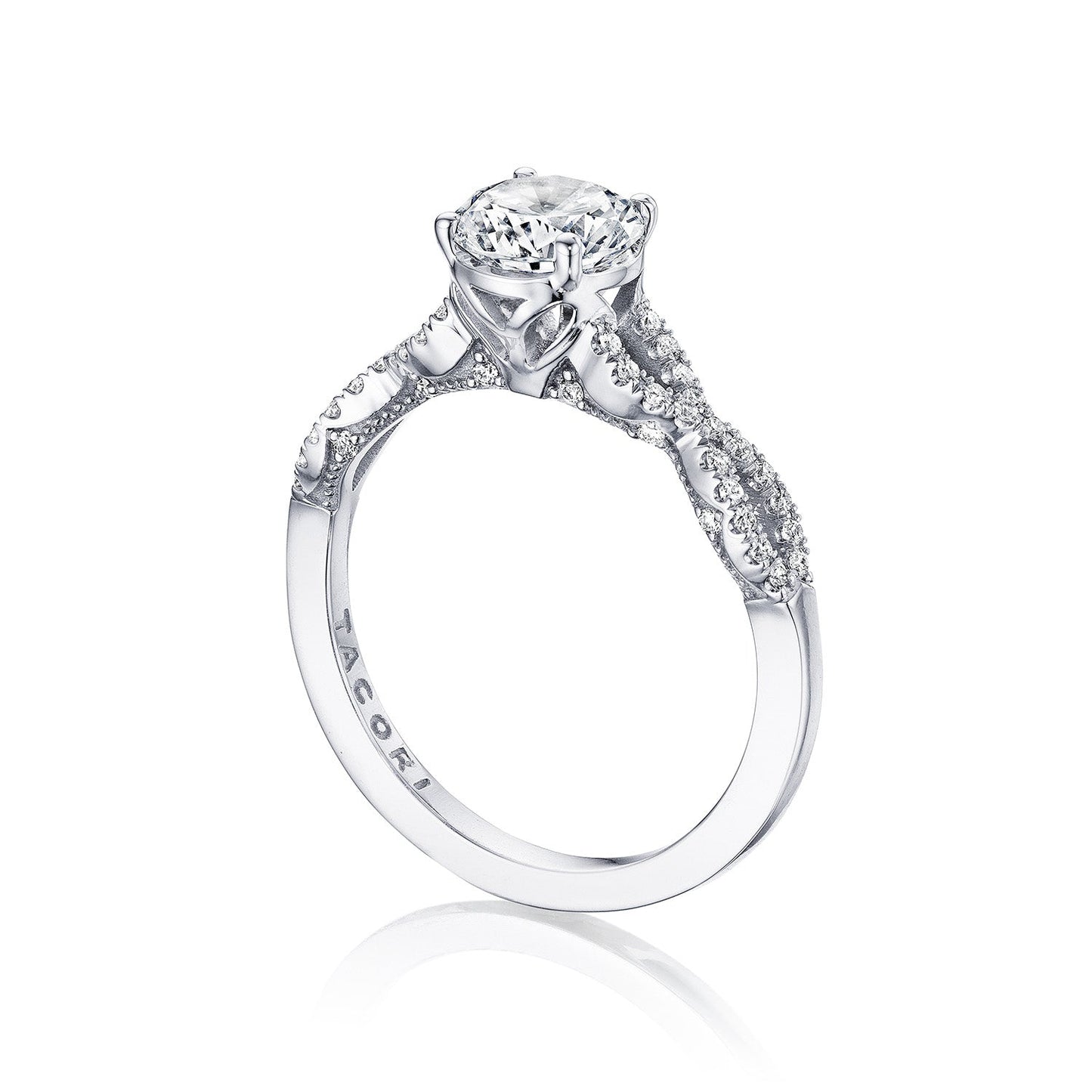 Introducing the Tacori Coastal Crescent engagement ring, a stunning piece crafted from 14K white gold. This exquisite ring showcases a large round brilliant diamond as its centerpiece, complemented by smaller diamonds adorning the band. Inspired by Tacori's renowned gemologists, the design features intricate metalwork and decorative settings that highlight its detailed craftsmanship.