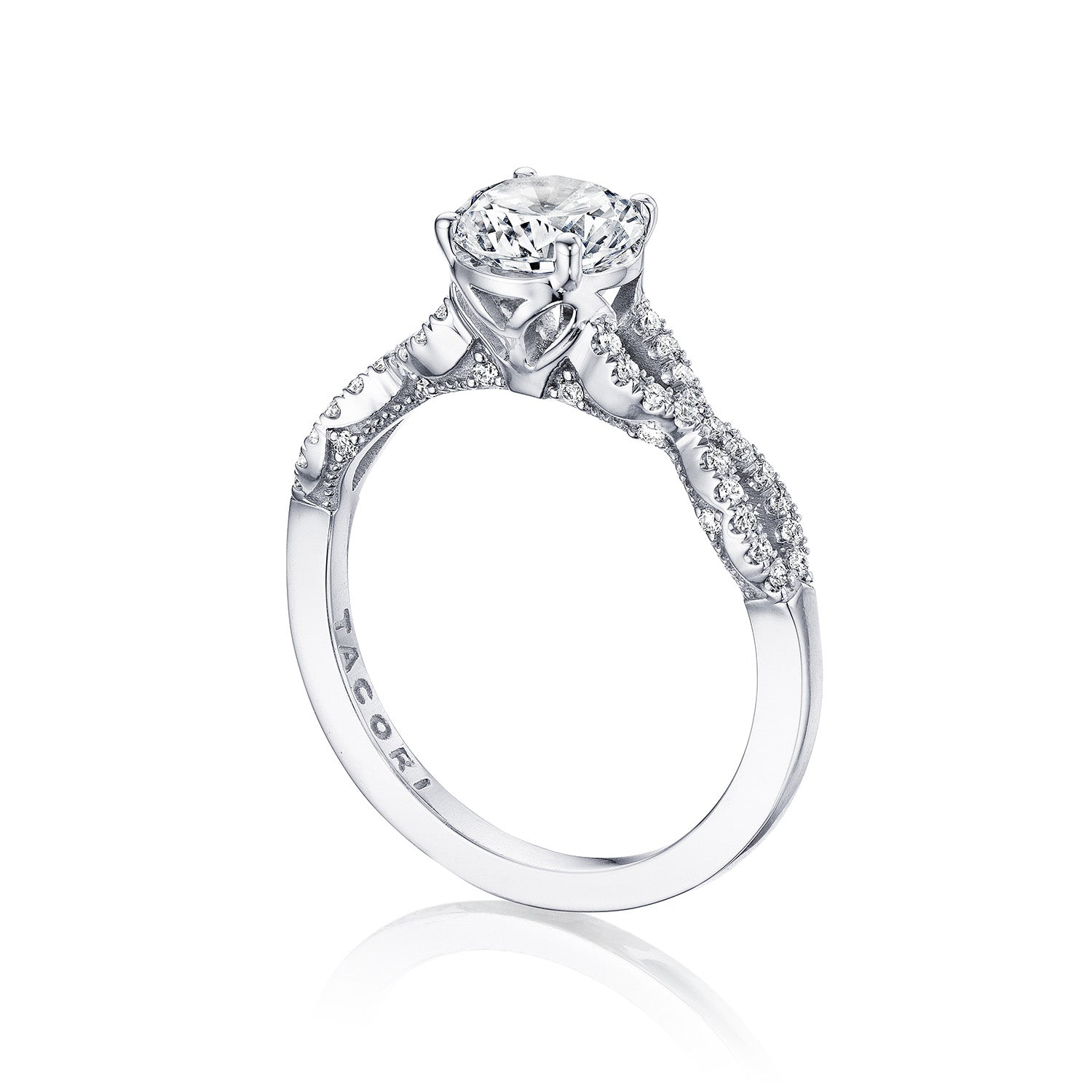 Introducing the Tacori Coastal Crescent engagement ring, a stunning piece crafted from 14K white gold. This exquisite ring showcases a large round brilliant diamond as its centerpiece, complemented by smaller diamonds adorning the band. Inspired by Tacori's renowned gemologists, the design features intricate metalwork and decorative settings that highlight its detailed craftsmanship.