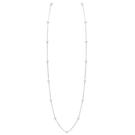 This necklace from Mikimoto, known as the 18K White Gold Akoya Cultured Pearl Station Necklace, showcases small Akoya Cultured Pearls spaced evenly along its thin silver chain. Its elegant and simple design exudes a delicate and minimalist appearance against a plain white background.