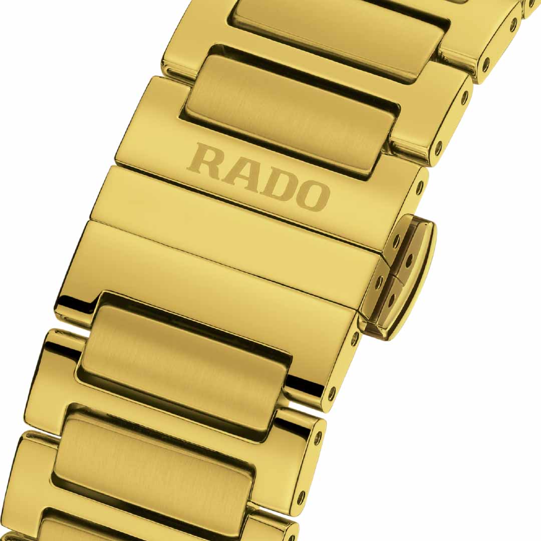 Close-up of a yellow gold wristwatch band from the RADO DiaStar Original Automatic 38mm Watch, with the brand name "RADO" engraved on one of the links. The band showcases a polished, shiny surface and incorporates an automatic movement, complete with a clasp for fastening.