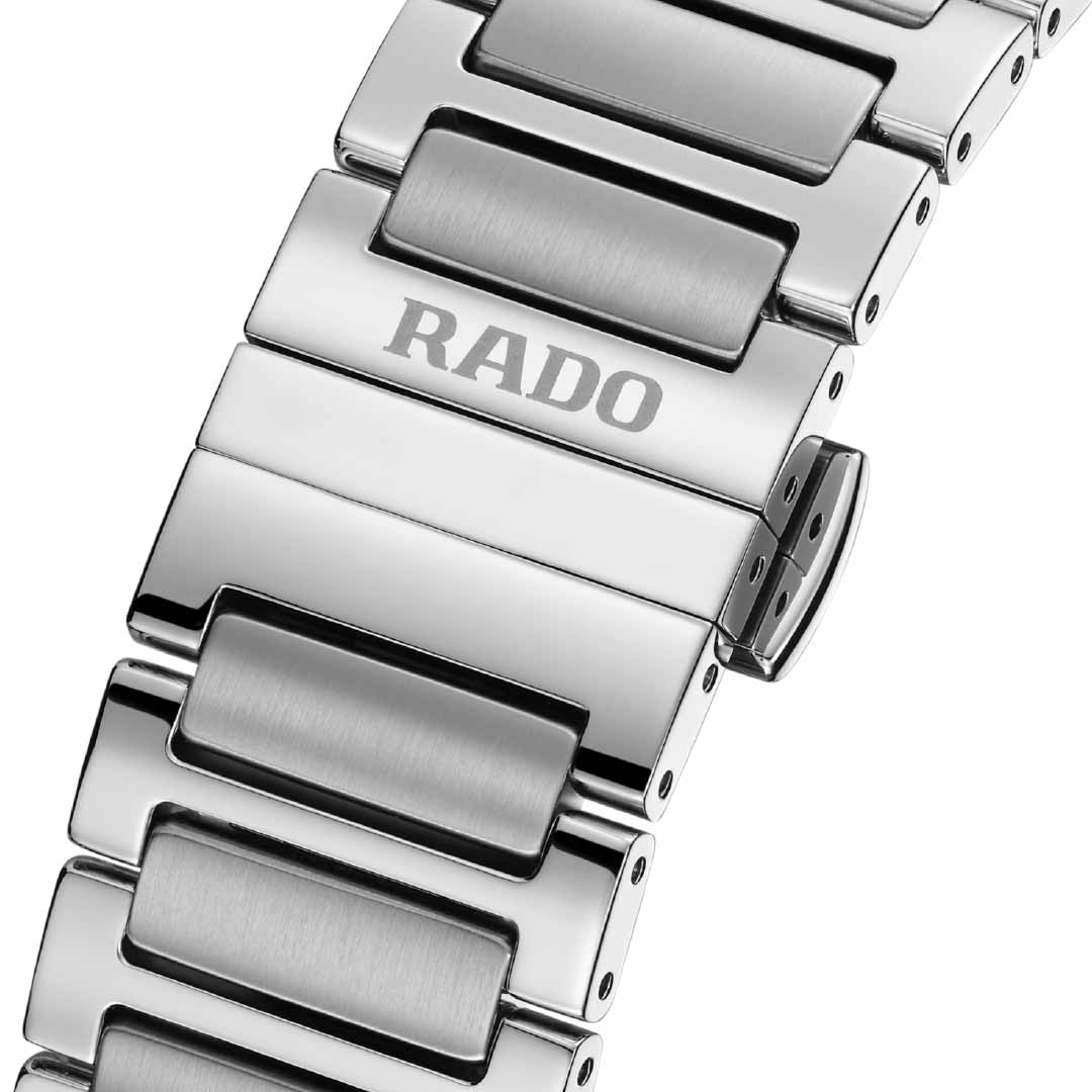 The RADO DiaStar Original Skeleton Automatic 38mm Watch features a close-up of its silver metal band, highlighting the polished and brushed links with "RADO" engraved on a central link. Beneath the sapphire crystal, it showcases the intricate R808 automatic calibre. An elegantly visible clasp is positioned on the right side.