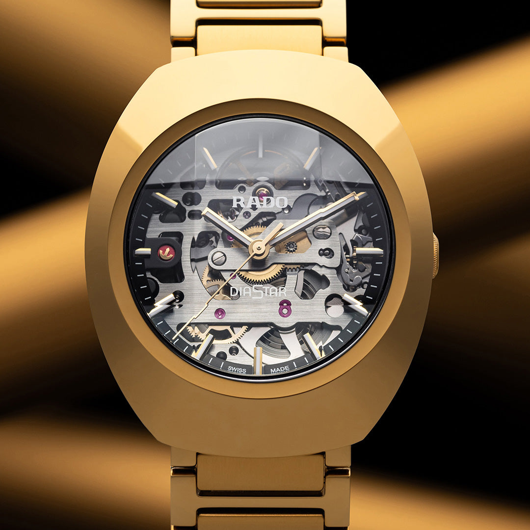 The RADO DiaStar Original Skeleton Automatic 38mm Watch features a gold-coloured Ceramos bezel and skeleton dial to display its automatic movement, set against dramatic gold and black streaks.