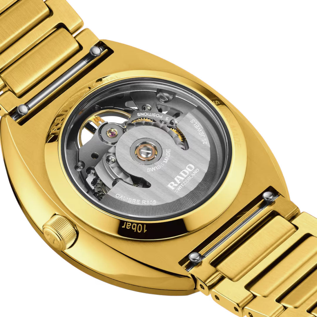 Close-up of the back of a gold RADO DiaStar Original Automatic 38mm Watch, showcasing its transparent case back with visible skeleton movement and intricate mechanisms. The gold bracelet is also visible.