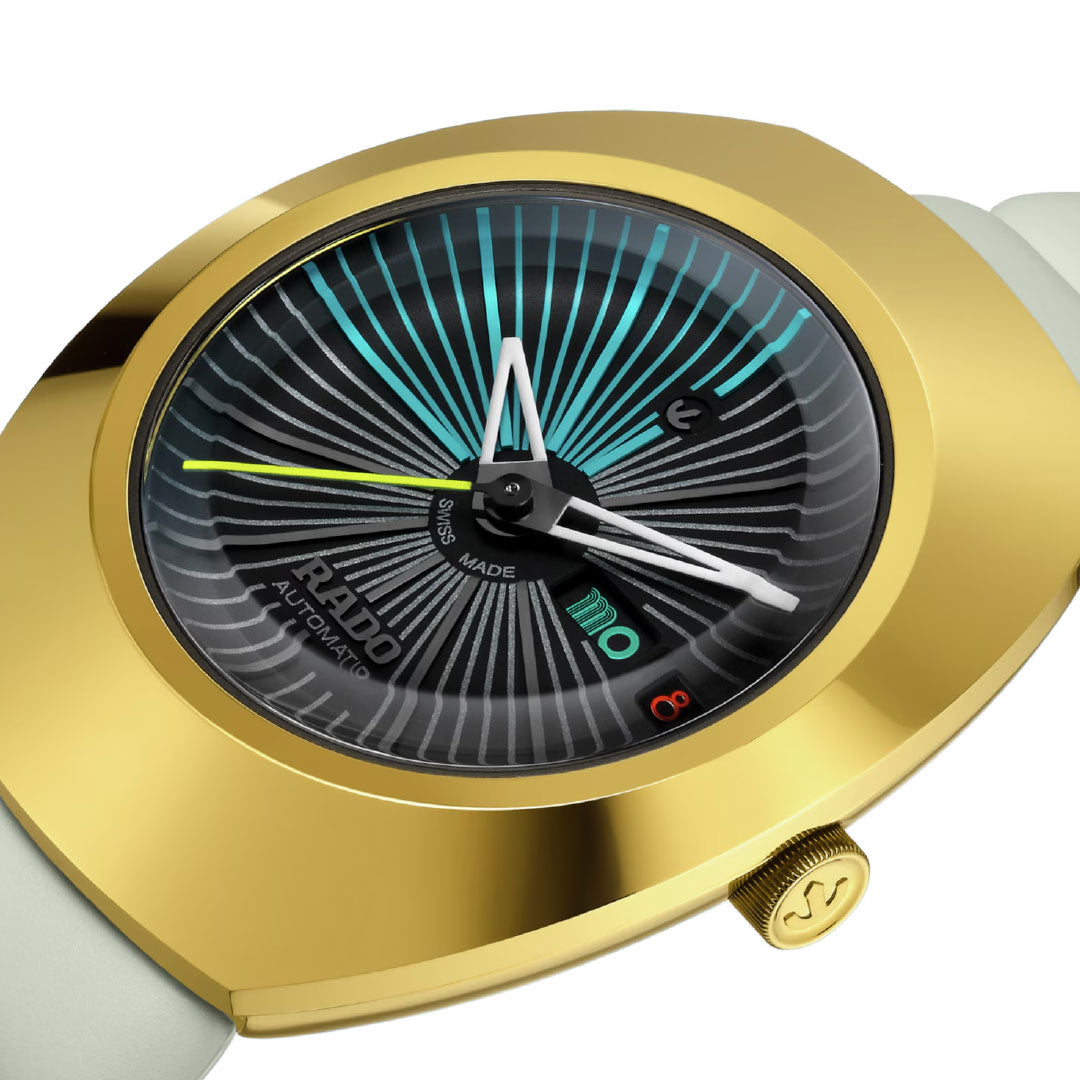 The RADO Diastar Original X Tej Chauhan Special Edition Automatic 38mm features a gold case, black patterned dial with turquoise and white lines, Swiss craftsmanship, turquoise and white hands, white strap, and "Rado Automatic" on the face.