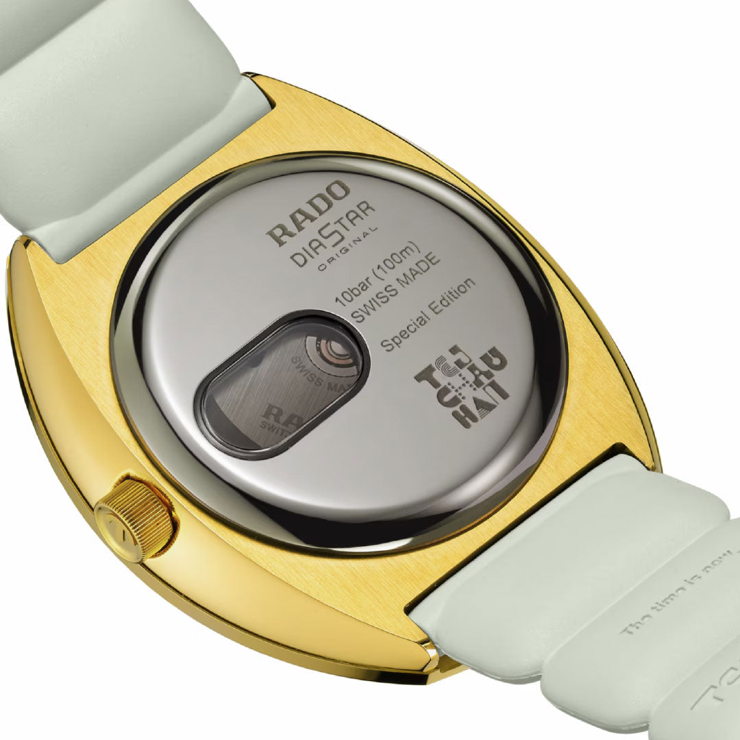 Close-up of the RADO Diastar Original X Tej Chauhan Special Edition Automatic 38mm watch's gold-toned case back with a white strap, engraved "Swiss Made," and a display window revealing Swiss craftsmanship.