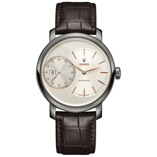 The RADO DiaMaster Grande Seconde Automatic 43mm watch features a sleek silver-tone design with an elegant white textured dial and silver hour markers. Encased in a sophisticated ceramic case, it includes a date window at the 9 o'clock position and a small seconds subdial, all beautifully paired with a brown leather strap.