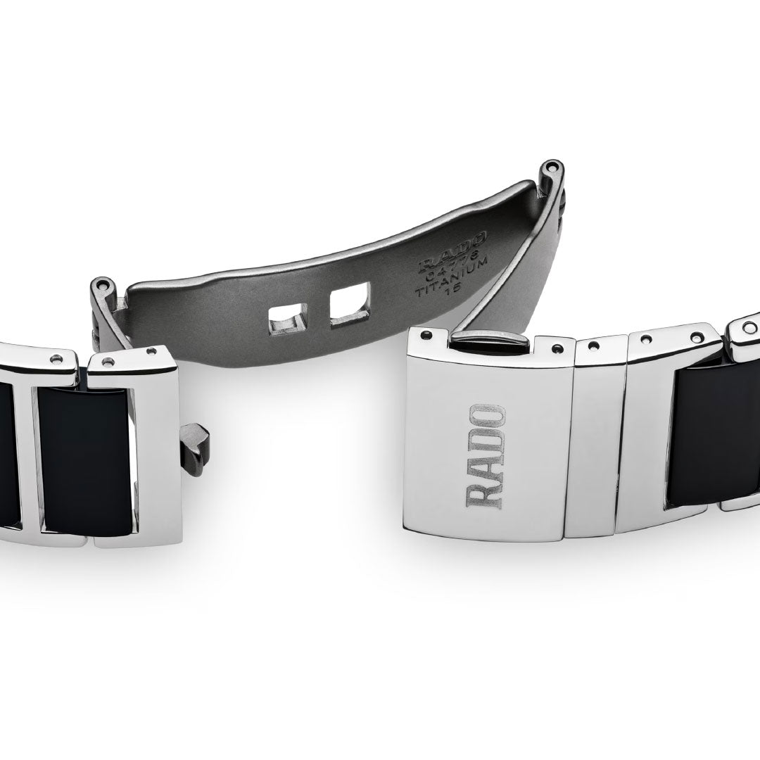 A close-up of the RADO Intergal Diamonds Quartz 31mm Watch clasp, crafted from polished silver-tone titanium and high-tech ceramic, engraved with "RADO." The open clasp reveals its inner mechanism.