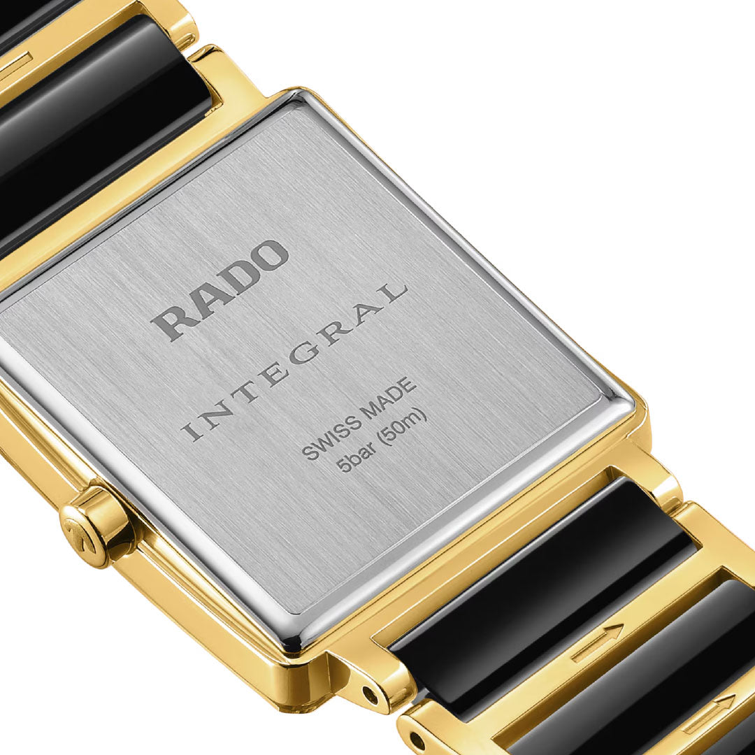 Close-up of the RADO Integral Diamonds Quartz 23mm Watch, highlighting its yellow gold and high-tech ceramic bracelet, rectangular stainless steel case, "Swiss Made" engraving, and 5 bar (50m) water resistance.