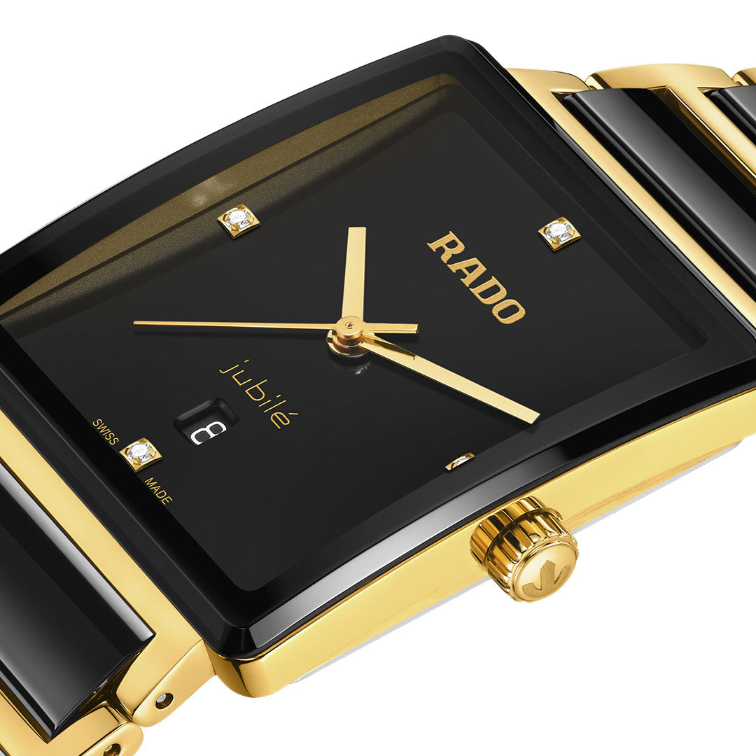 Close-up of the RADO Integral Diamonds Quartz 31.5mm Watch featuring a rectangular black dial with diamond hour markers, gold hands, date display, and a yellow gold bracelet with black ceramic inlays and sapphire crystal.