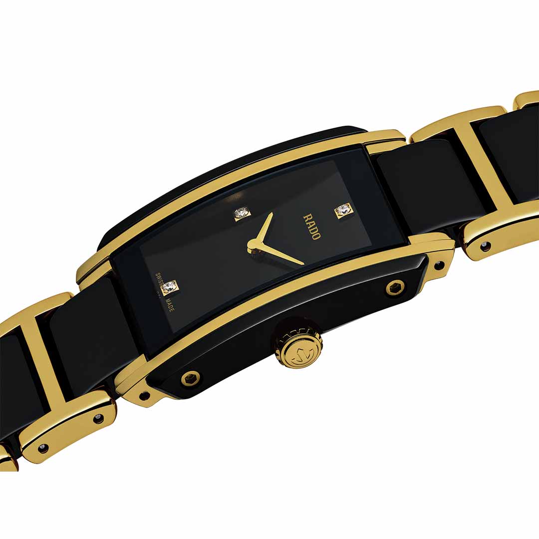 The RADO Integral Diamonds Quartz 22.7mm Watch by RADO features a sophisticated black and gold design with a rectangular face. It incorporates advanced ceramic components, complemented by a black strap with gold highlights, and an elegant dial embellished with small square markers that convey minimalist elegance.