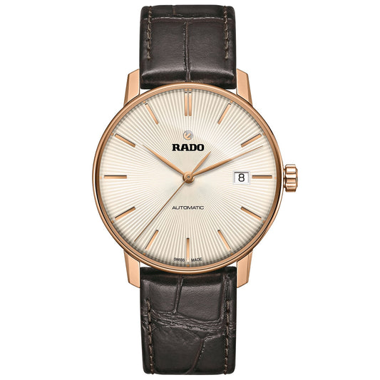 The RADO Coupole Classic Automatic 37.7mm Watch features a white textured dial adorned with gold hour markers, a date window located at 3 o'clock, and the "Swiss Made" label at the bottom. Enclosed in a gold case and safeguarded by a sapphire crystal, it comes with a dark brown leather strap showcasing visible stitching.